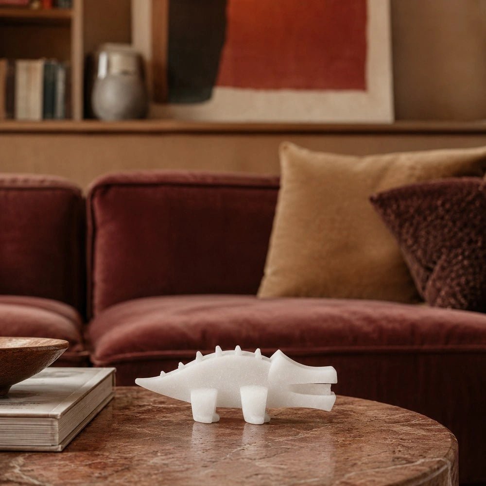 Salto Crocodile Sculpture styled on a pale coffee table with stacked books and bowls, creating a playful dark decorative accent in a warm interior.