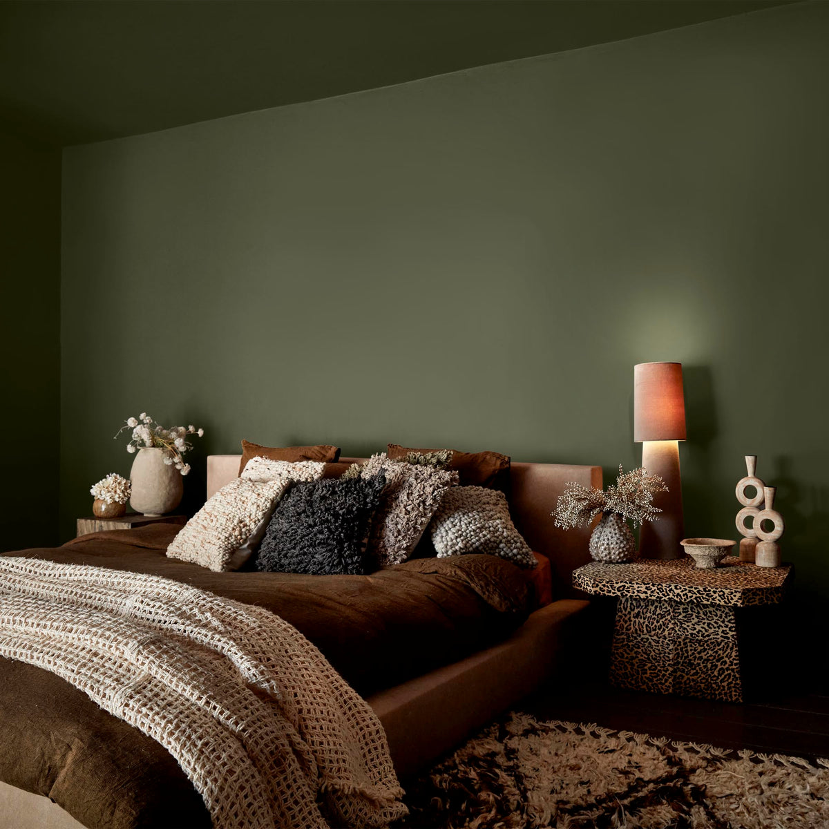 Abigail Ahern Seagrass Meadow paint – a sumptuous warm olive green enveloping a beautifully layered bedroom with luxurious textured soft furnishings
