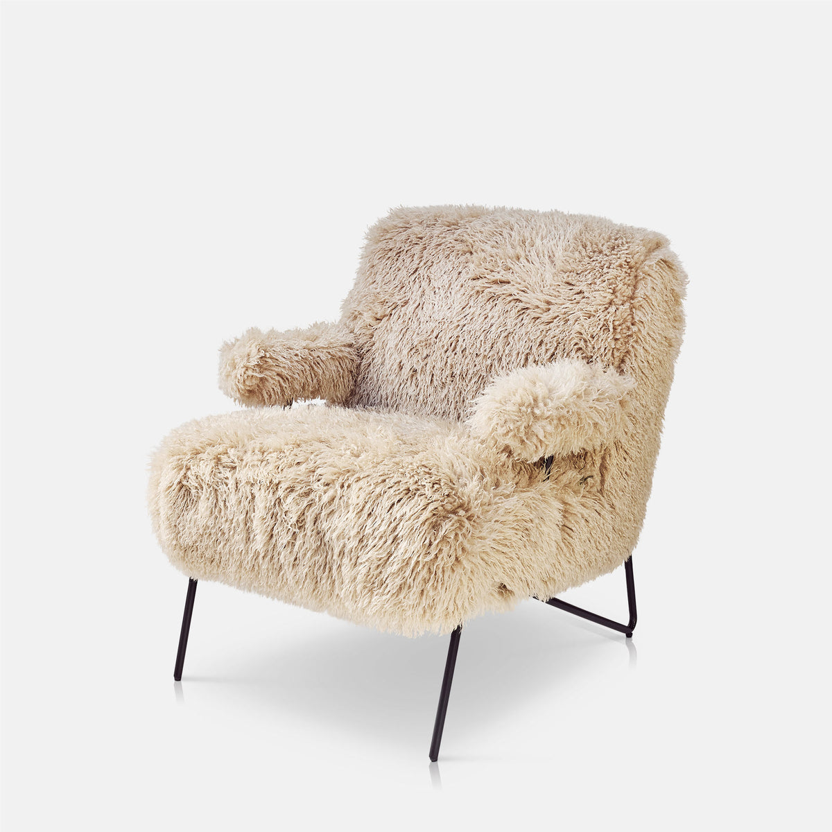 Selma faux fur armchair upholstered in soft cream faux fur with a curved contemporary silhouette, rounded backrest and generously cushioned seat. Luxury accent chair designed for living rooms, bedrooms and reading corners, bringing warmth, texture and comfort while adding sculptural form and understated elegance to modern and eclectic interiors.