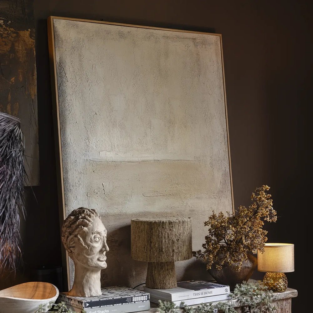 Serenity canvas art features a pale abstract composition with subtle textured layers in a slim frame, displayed above a console with sculptural objects and books.
