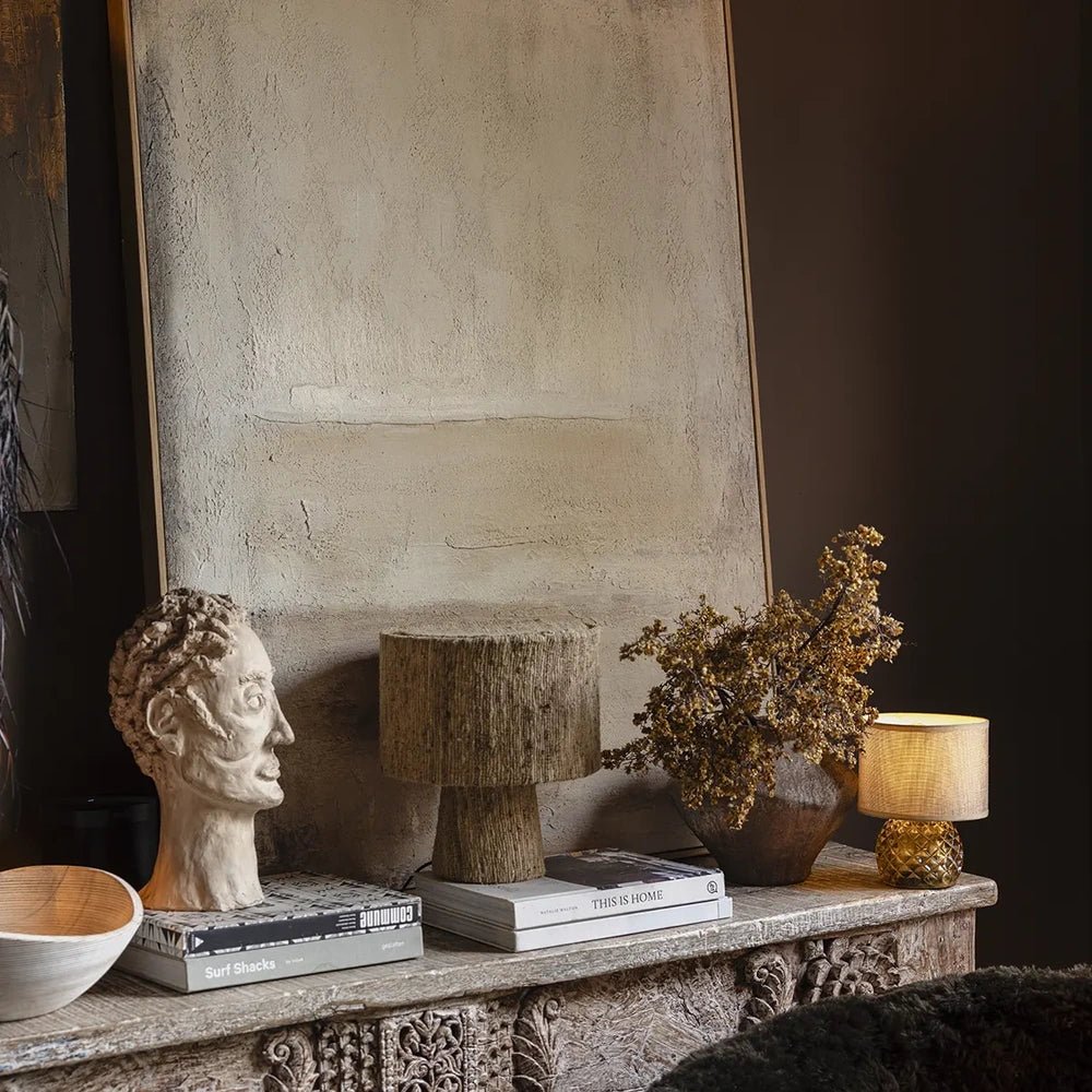 Serenity canvas art shows softly layered cream and neutral tones with subtle surface texture, displayed above a console styled with books, sculpture and dried foliage.