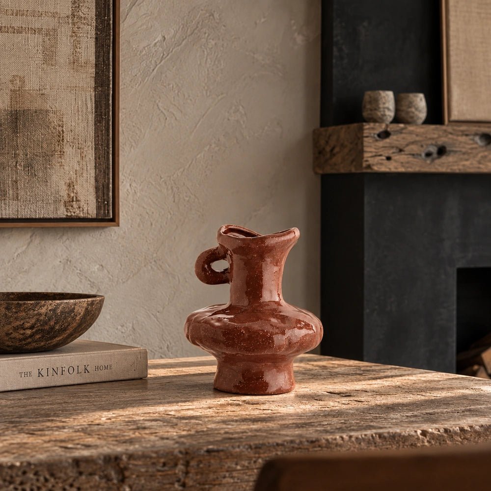 Sylvie Stoneware Vase with sculptural curved form and glossy earthy surface, styled on a textured coffee table beside a book and decorative bowl.
