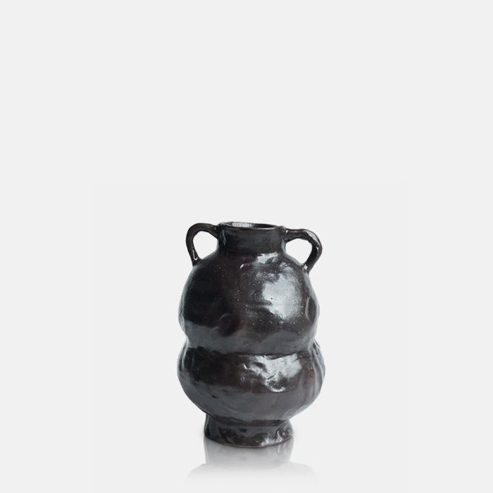 Cutout image on a white background of a organic, curved brown ceramic vase with two small handles.