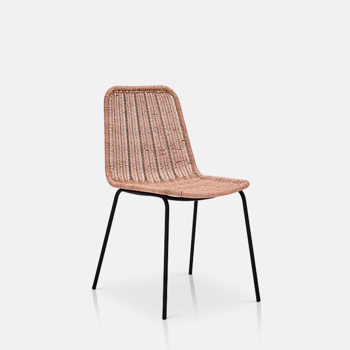 A closeup of the Tatum Chair, a natural rattan woven chair in a contemporary style with slim black metal legs.