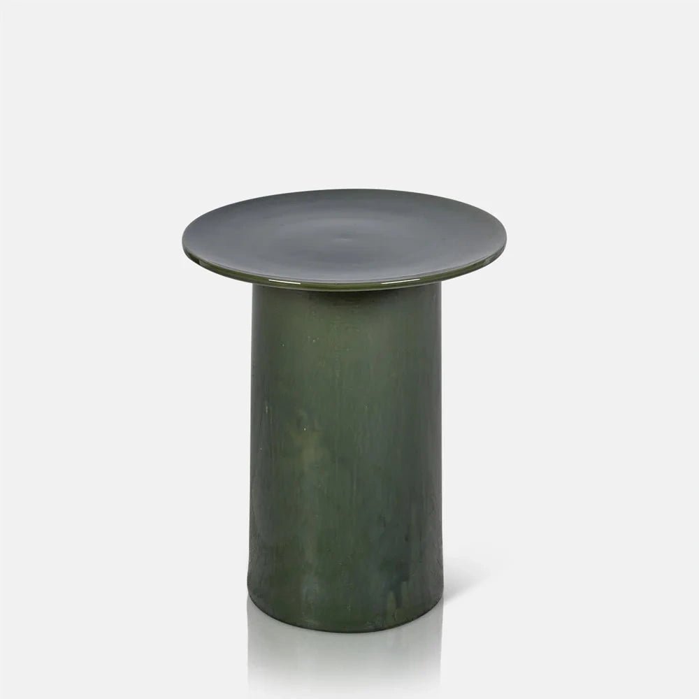 Thayer stoneware side table with a broad round green top and tall cylindrical base, showing a glossy mottled finish and softly irregular surface tones.
