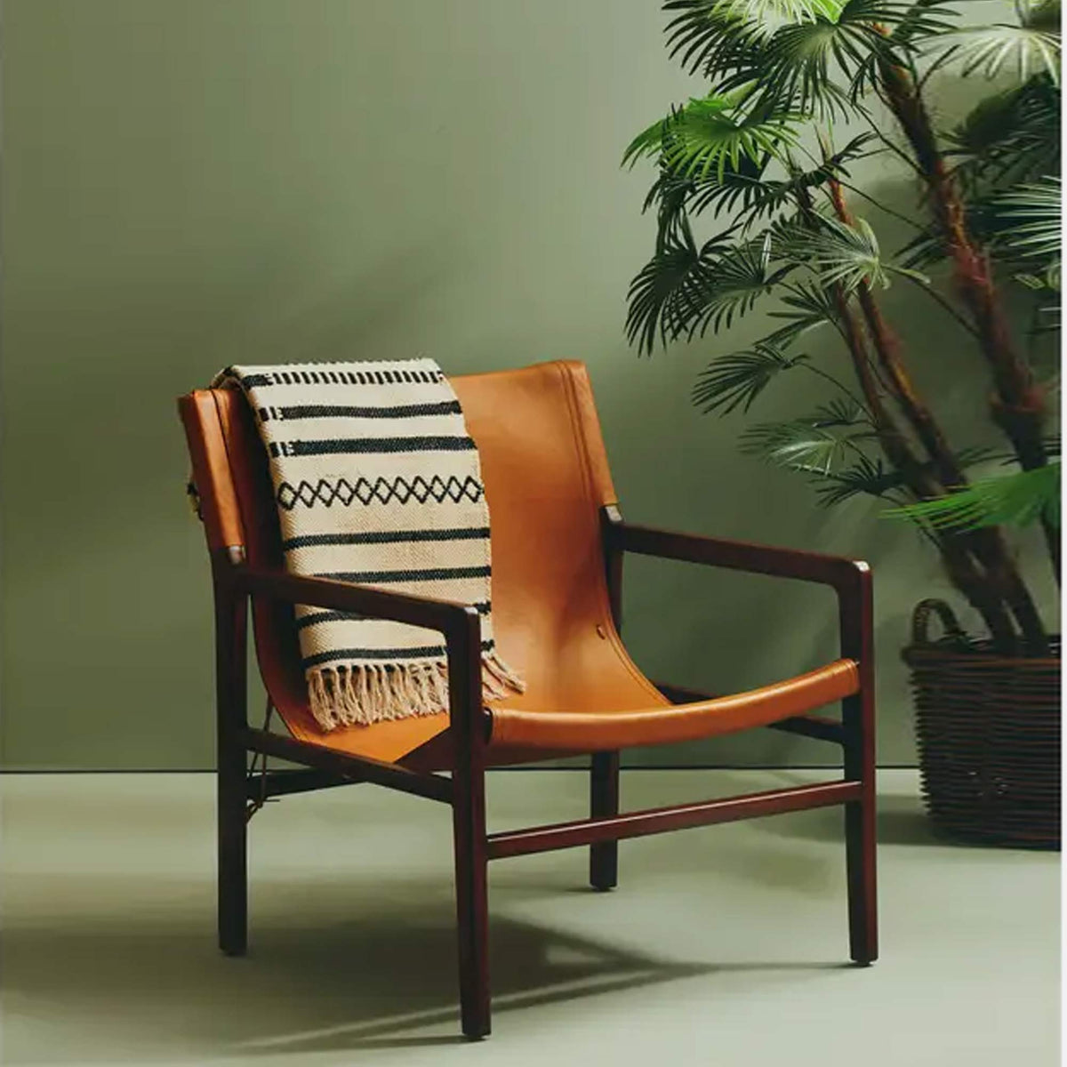 The Tobin Leather Sling Chair, a mid-century style low square chair in teakwood with a warm brown leather seat.
