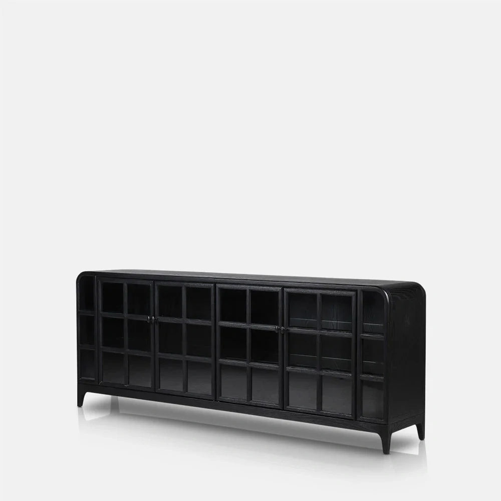 Trumbull wooden sideboard in black with a long rectangular shape, gridded glazed doors, rounded outer corners and short tapered legs, viewed from a slight angle.