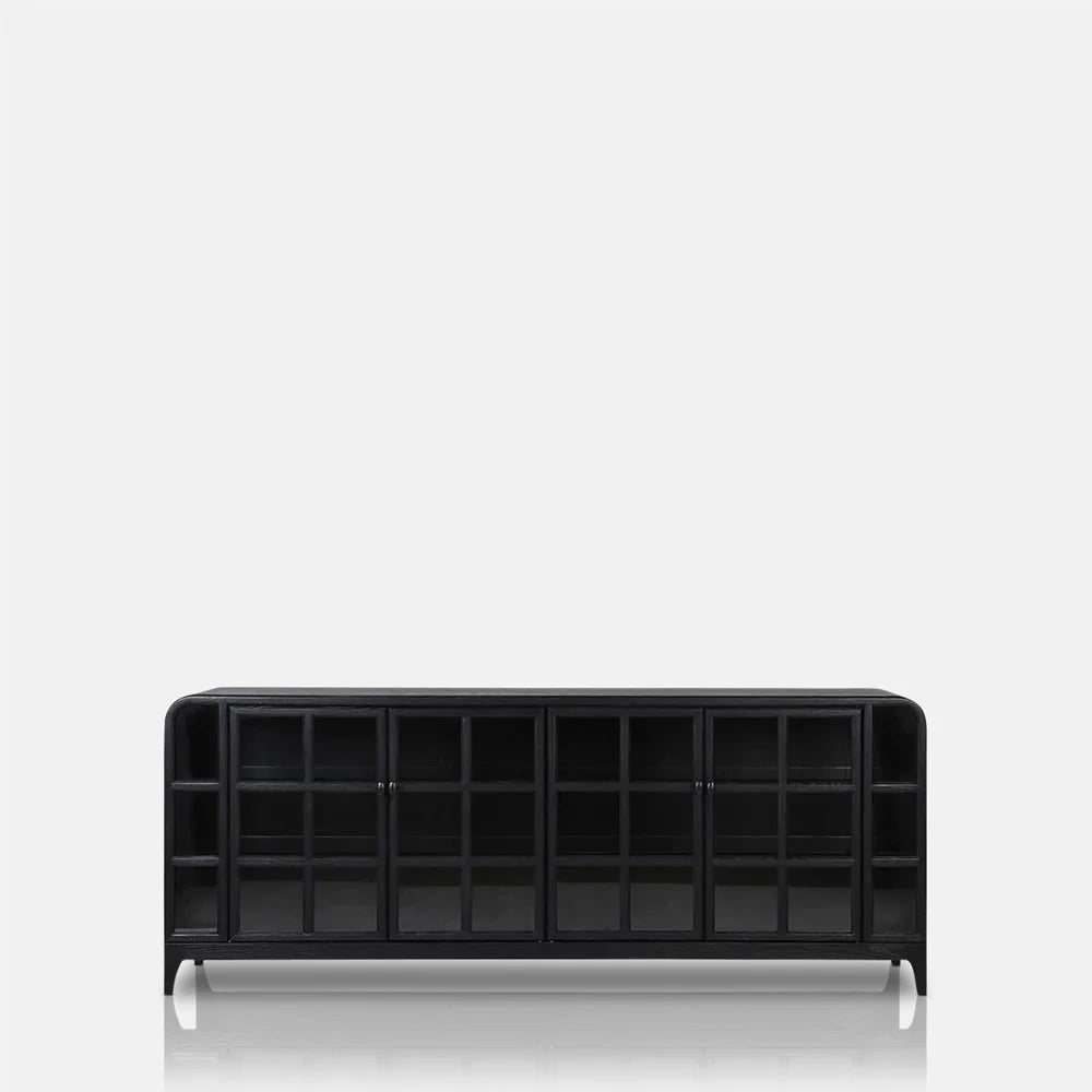 Trumbull wooden sideboard in black with gridded glazed doors, a long low rectangular body, softly rounded corners and short tapered legs, viewed from the front.