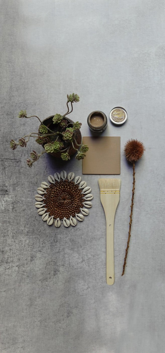 A light sandy brown paint swatch flatlay styled with a houseplant and home accessories. Neutral paint colour for a natural style home. 