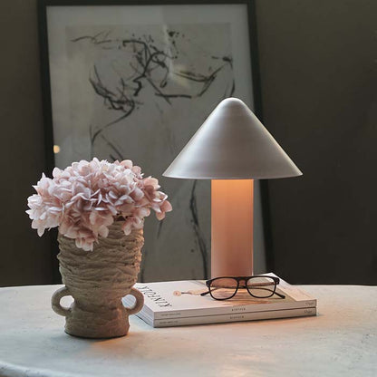 Blush coloured metal table lamp with cone shaped shade.