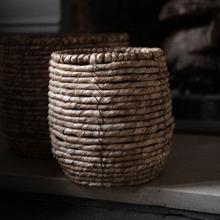 Round, brown woven basket sat on a fireplace