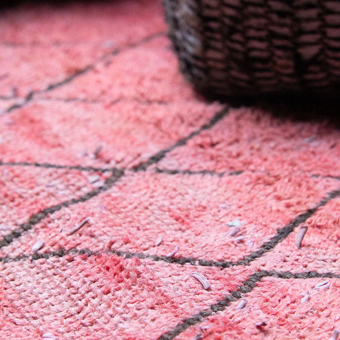 Faded red and black diamond pattern on vintage berber rug.