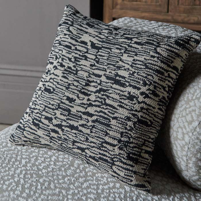 Square monochrome cushion in woven abstract design.