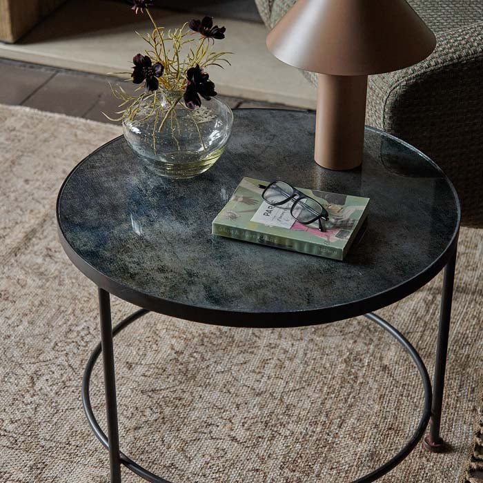 Blue printed glass coffee table with a clear glass vase and brown lamp on top