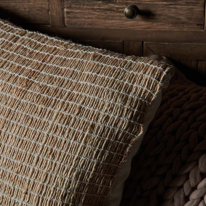 Woven jute cushion cover with white stitching.