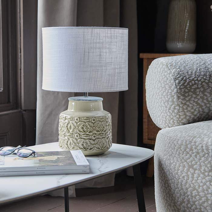 Glossy beige ceramic table lamp with white drum shade.