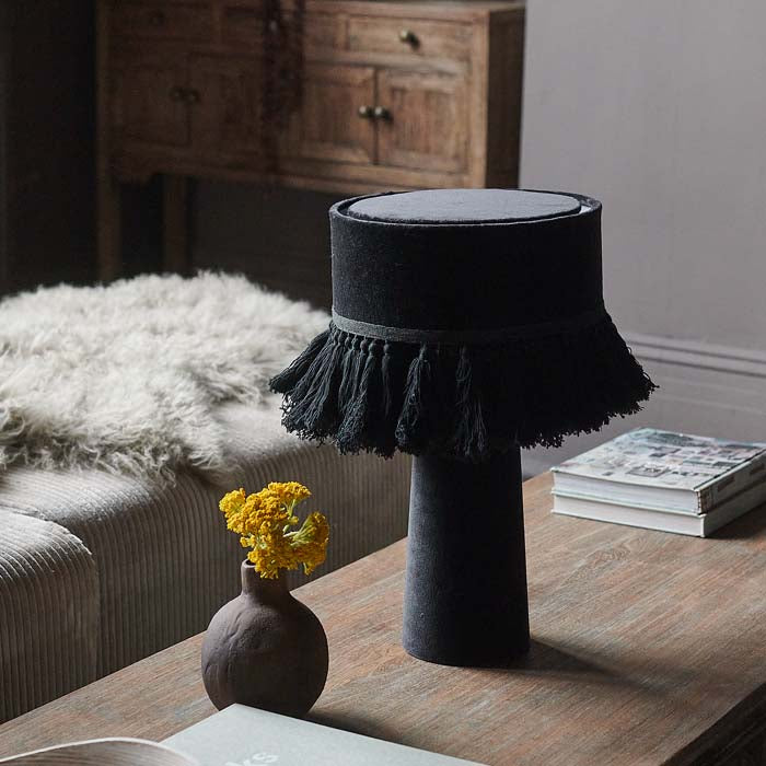 Black velvet table lamp on wooden coffee table.