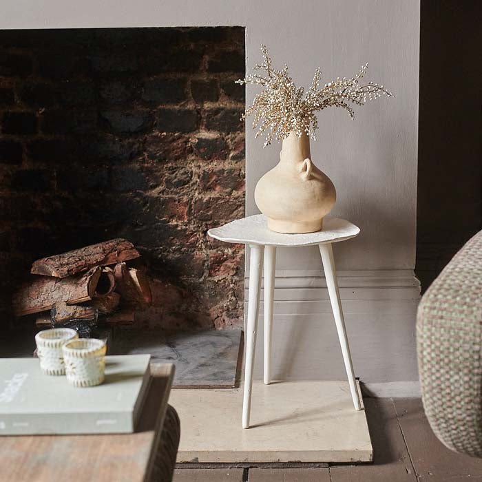 Small white metal side table with organic table top shape and three legs.