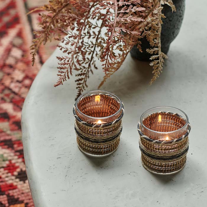 Two glass candleholders covered in woven brown and black fabric.