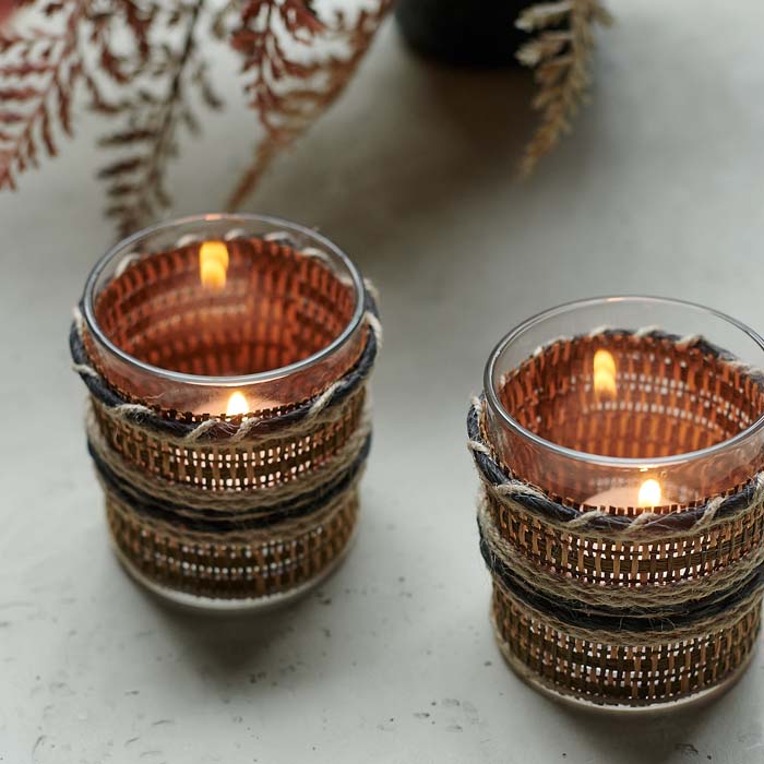 Tealight candles glowing through woven fabric glass candle holders.