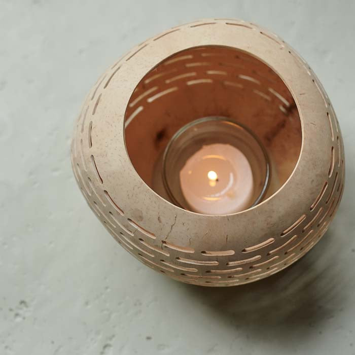 Tealight candle glowing inside a coconut candle holder.