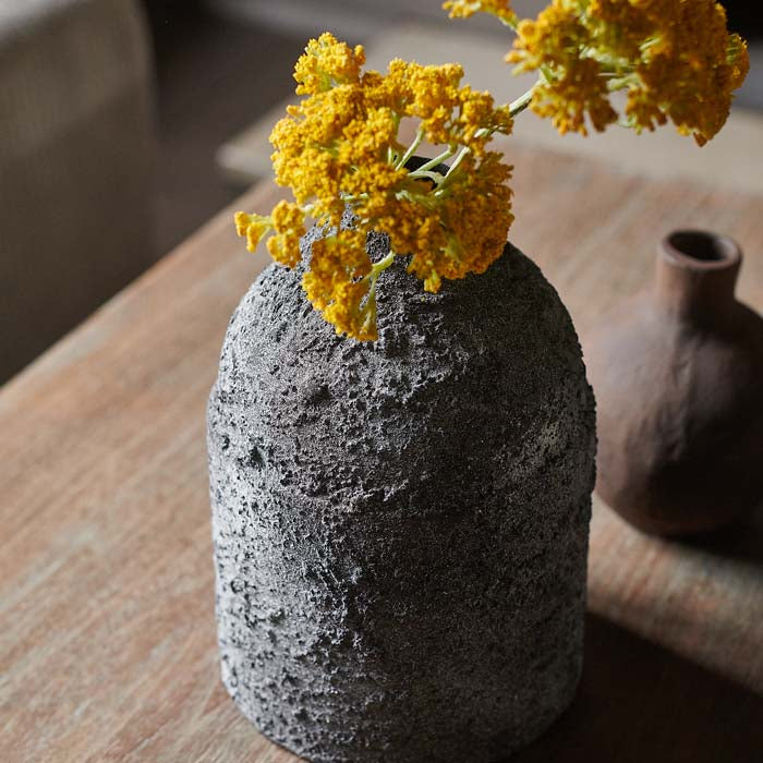 Single yellow faux flower stem in a dark grey vase
