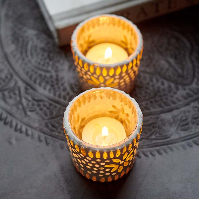 Tealights glowing inside two mosaic votives.