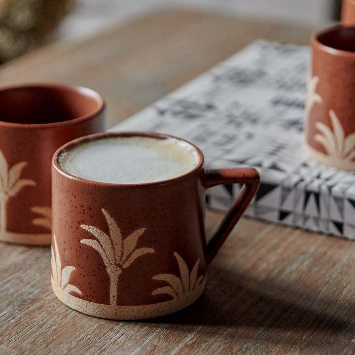 Speckled terracotta glazed mug with palm tree motif.
