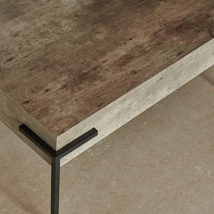 Black metal leg at corner of square shaped faux concrete coffee table.