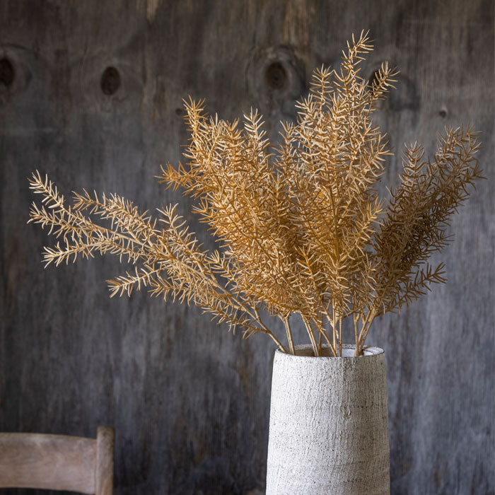 Orangey-brown textural faux foliage stems placed in a tall grey vase