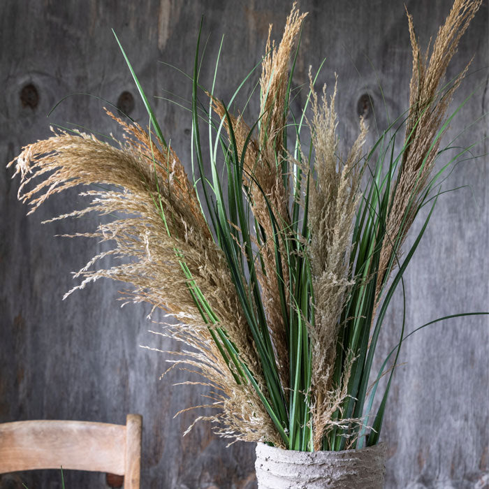 Large bunch of dried pampas grass stems with artificial green leaves