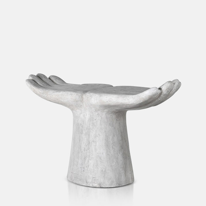 A cutout of the Aimee Abstract Stool, a textured white resin stool in the shape of two open hands.