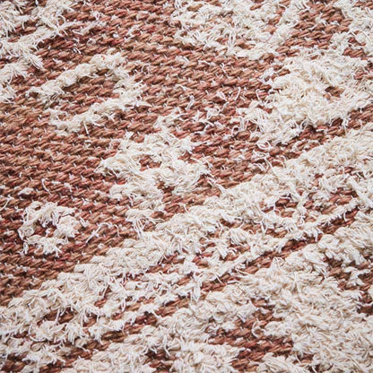 Woven pattern on dusky pink and cream rug.