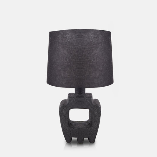 Black sculptural lamp base with cut-out design and a black cotton drum shade.