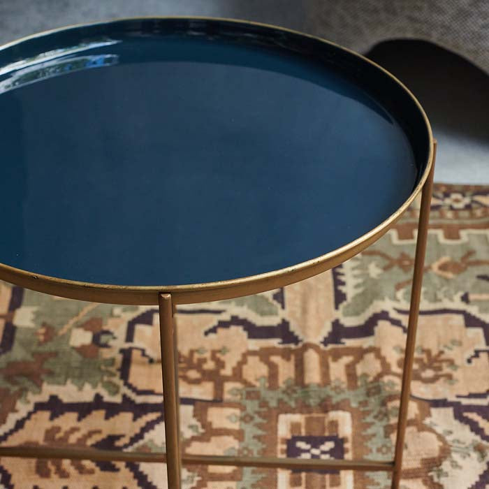 Blue enamel tray table with a gold foldable frame on a patterned rug