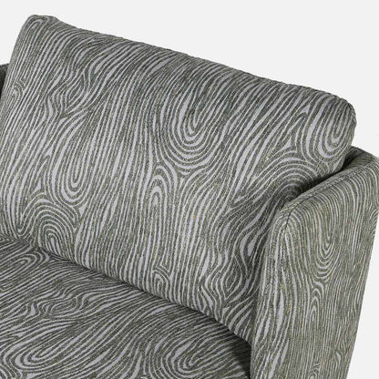 An upholstered grey armchair with a raised green wavy pattern.