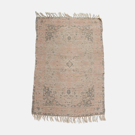 A large woven jute rug with tasseled edges, in pink and brown subtle pattern.
