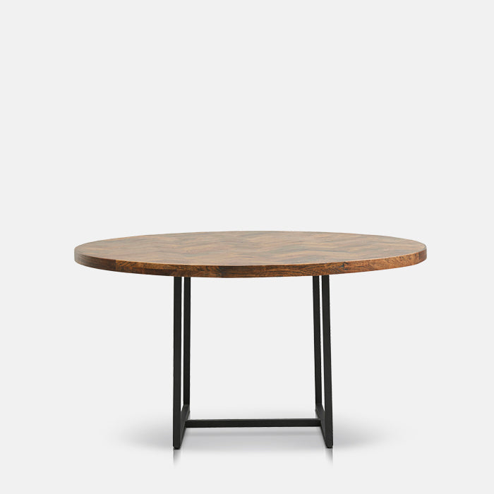 Round mango wood dining table with black metal U-shaped legs joined by centre bar.