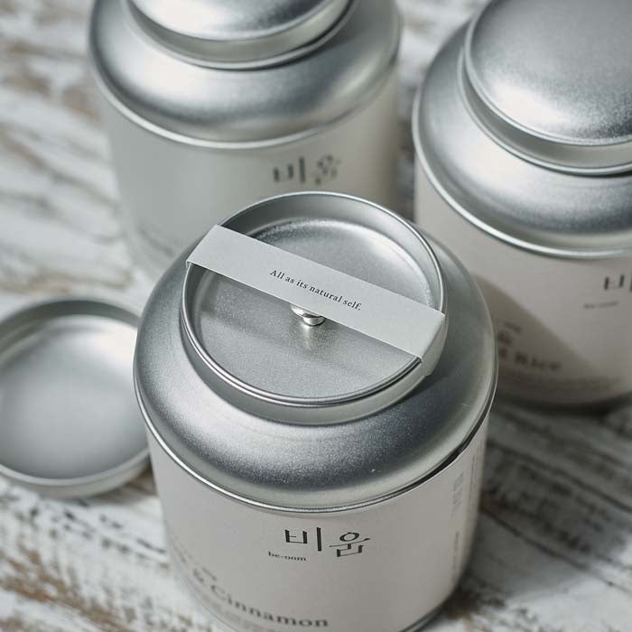 Round silver loose leaf tea tin with its lid off revealing a message banner across the top
