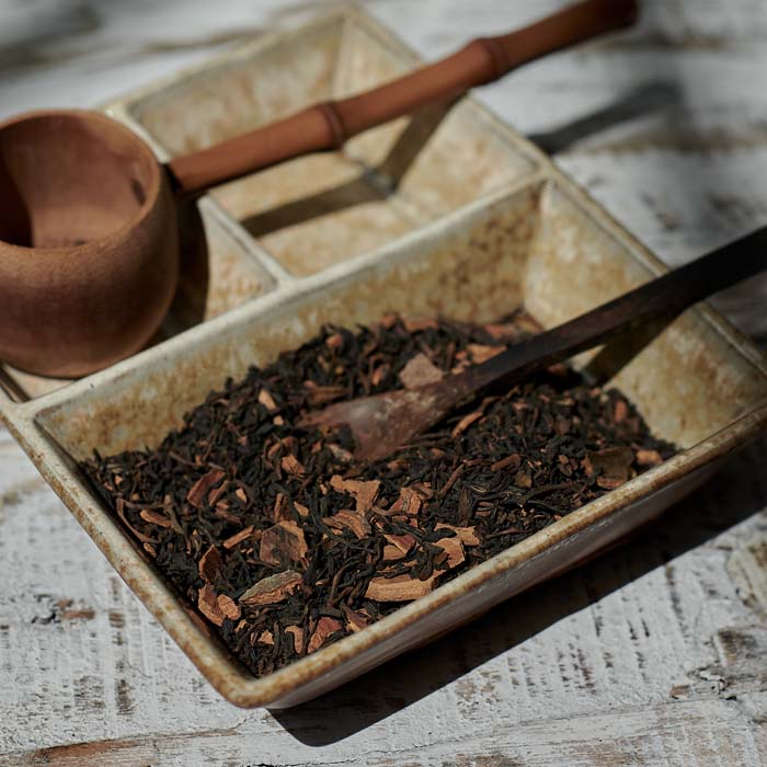Loose leaf tea inside a speckled brown ceramic dish.