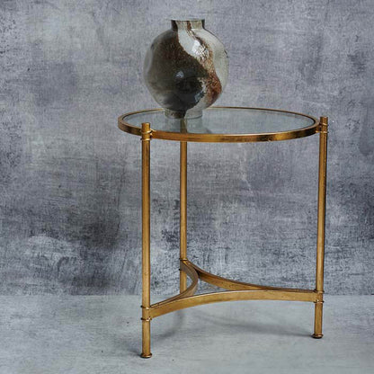 Round glass table with a golden frame and a brown glass vase on top