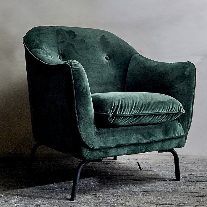 Large armchair with black metal legs, finished in a dark emerald green velvet fabric.