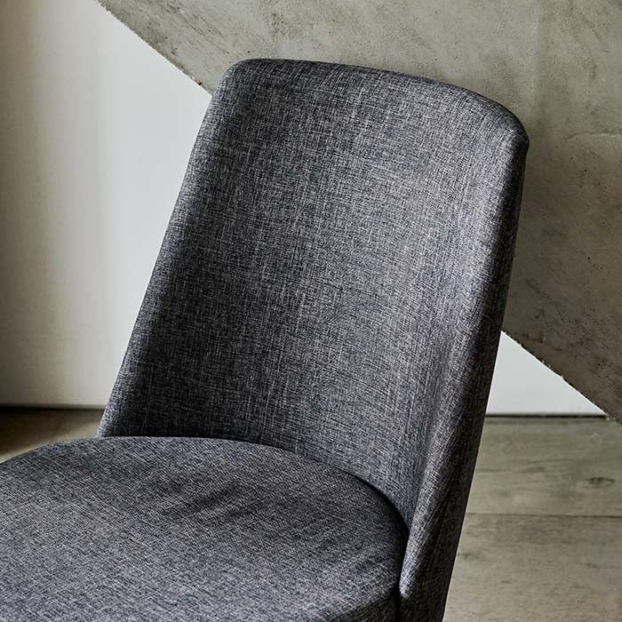 The curved back of an upholstered chair in grey finish.