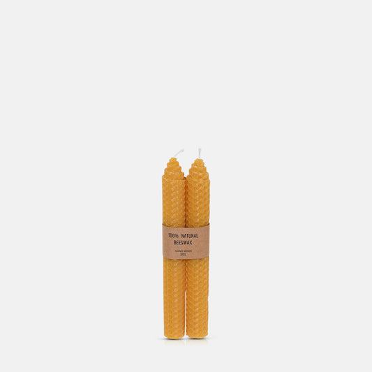 Set of two golden yellow beeswax candles with honeycomb pattern texture.