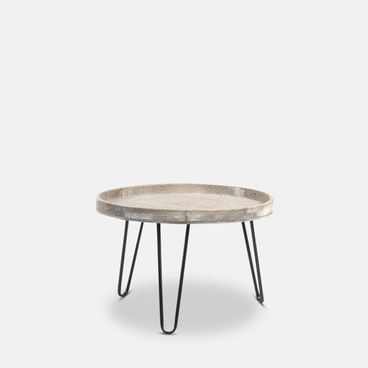 Small round wooden coffee table, in white-wash finish, with three black iron legs.