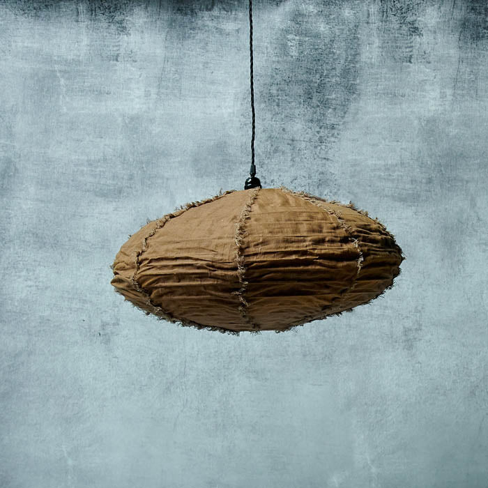 Oval shaped brown fabric pendant light shade hanging from a long black wire on a grey wall