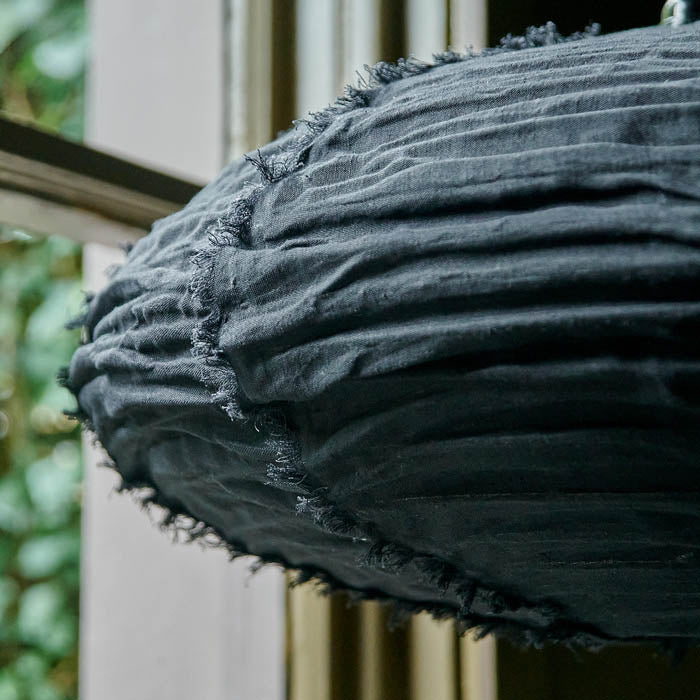 Crinkled oval shaped fabric pendant shade in black with short tasseled lines on its surface