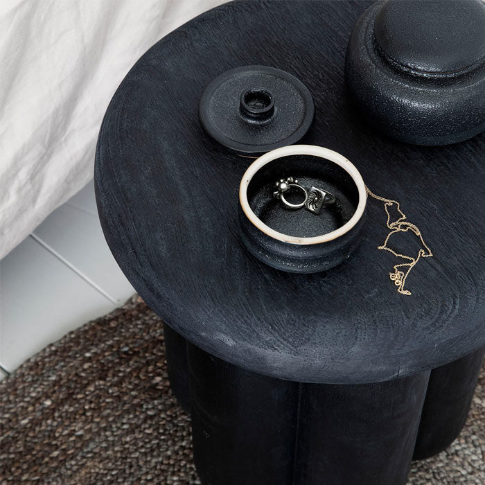 A round black wooden bed-side table.