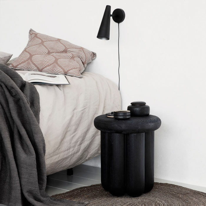 A black wooden side table in round shape, with curved leg design.