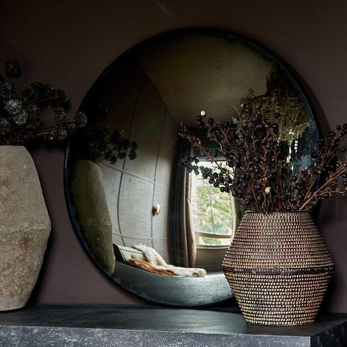 The Farah Convex Mirror, an oversized round mirror with a slim black frame, leaning against a wall.